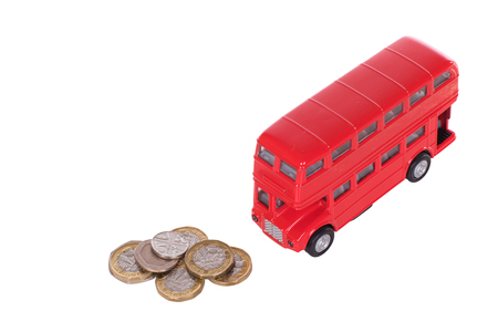 Red double-decker bus with a pile of loose sterling change in a concept of the costs of public transport in Britain isolated on whiteの写真素材