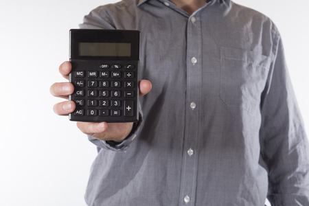 Man holding out a small manual calculator with a blank readout towards the camera in a torso view on whiteの写真素材