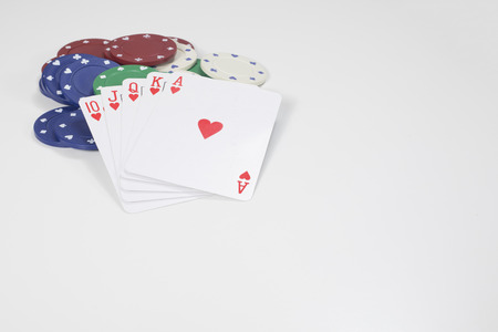 Winning poker hand showing a straight royal flush in hearts on a pile of casino chips over a white background with copy spaceの写真素材