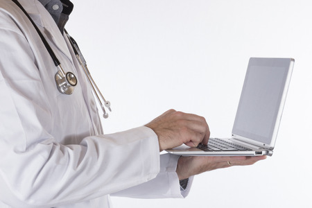 Male doctor using a handheld laptop computer to access patient records in a close up side view of...