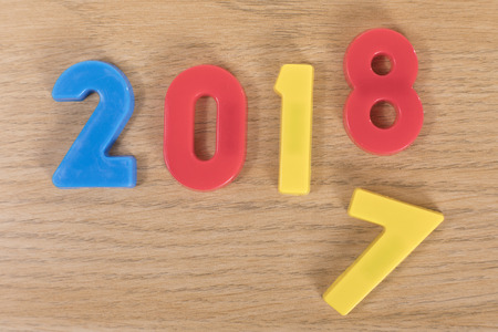 Colourful toy learning numbers on a plain timber background representing the year changing from 2017...