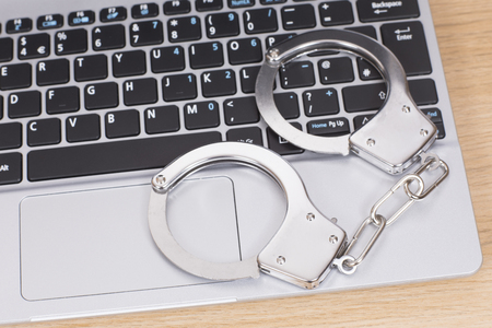 Handcuffs or manacles on a laptop computer lying on the keyboard conceptual of internet or online fraud and crimeの写真素材