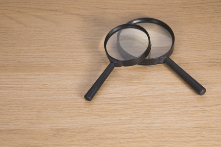 Two magnifying glasses lying on wooden tableの写真素材