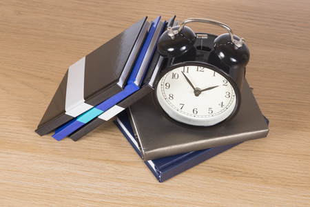High angle view of alarm clock standing among pile of notebooksの写真素材