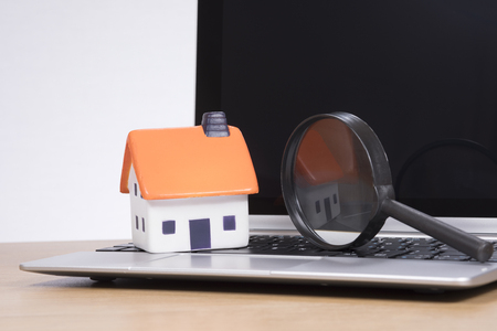 Miniature of house with magnifying glass standing on open laptopの写真素材