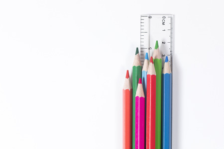 Set of colored pencil crayons with a ruler over a white background with copy space in an education, art and creativity conceptの写真素材