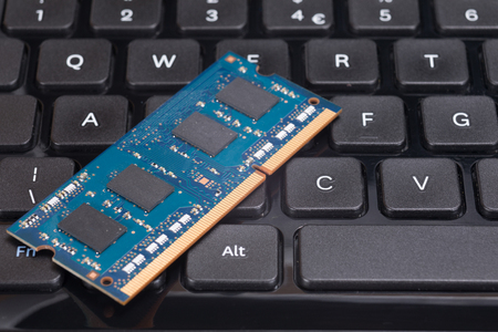 Close up of a blue computer chip circuit board on a black keyboard.