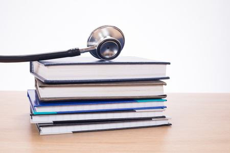 Stethoscope chestpiece lying on pile of planners against white backgroundの写真素材