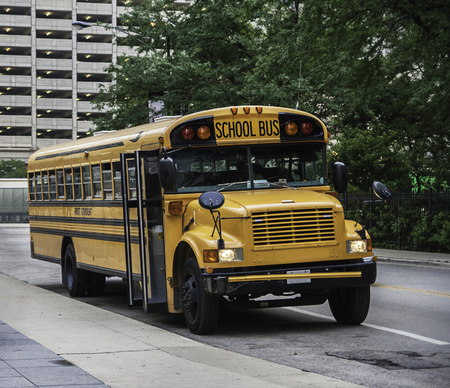 A school bus parked in a street, waiting for the students. Front view.