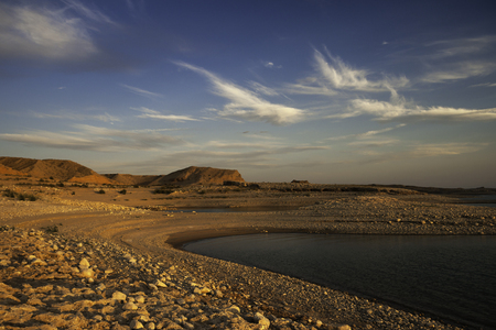 Vibrant and colorful muddy and rocky shores of the Lake Mead (Nevada) at sunset with blue sky and white clouds, summer 2007.の写真素材