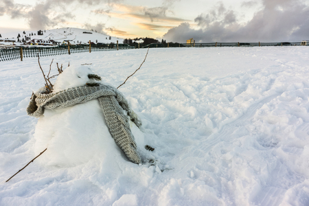 A snowman with a grey scarf in a snowfield at dusk - Winter 2017 - Vosges, France.の写真素材