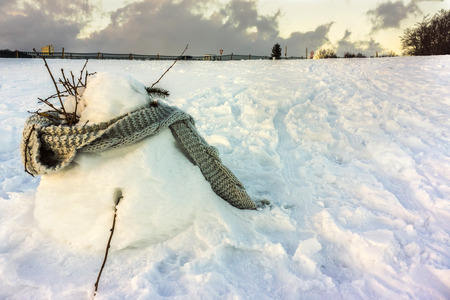 A snowman with a grey scarf in a snowfield at sunset - Winter 2017 - Vosges, France.の写真素材