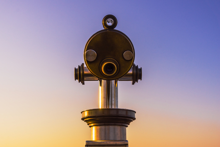 Close-up on binoculars with a beautiful evening sky with copy space.の写真素材
