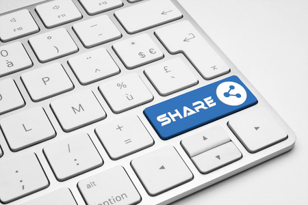 Share blue button with a network icon on a white isolated keyboard.の写真素材