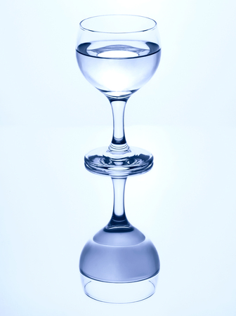 Single stemmed glass of water isolated on a white background with mirror reflection.の写真素材