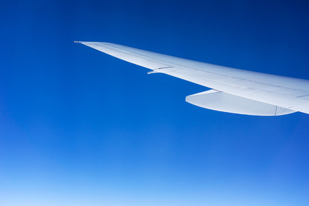 White airplane wing isolated on a graduated blue sky. Travel and flight concept.の写真素材