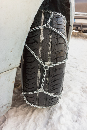 Closeup of snow chains mounted on a snowy car wheel.の写真素材