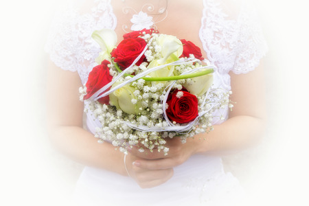 Close-up of a wedding bouquet of red flowers held by the bride.の写真素材