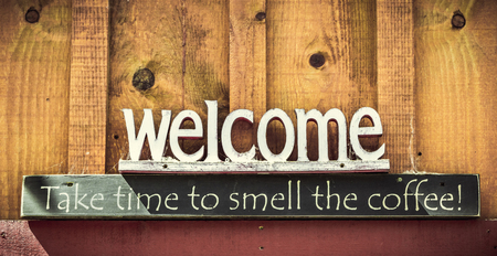 Welcome, Take time tu smell the coffee text sign on a wooden wall with copy space.の写真素材