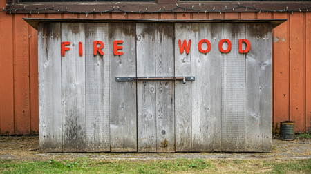 Firewood storage. Written with red lettering on weathered wood planks.の写真素材