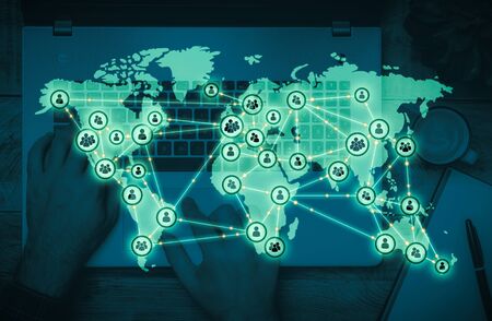 Worldwide digital communication network with top view of someone typing on a laptop keyboardの写真素材