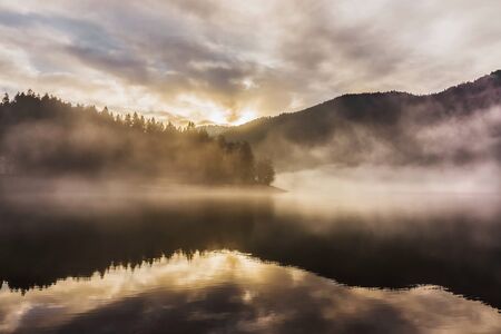 Sunset on the Kruth-Wildenstein Lake during a misty day of winter, Vosges, France.の写真素材