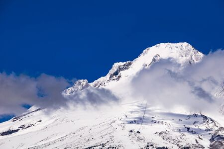 Snowy summit of Mount Hood with clouds and blue sky. Mt Hood National Park, Oregon, USA.の写真素材