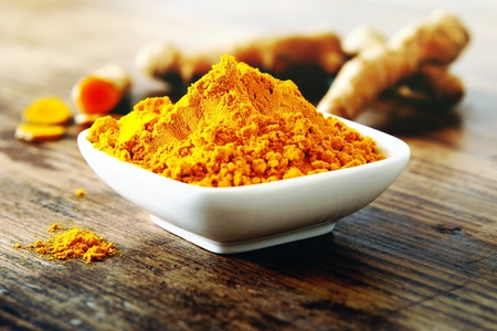 Turmeric powder and fresh turmeric roots on wooden backgroundの写真素材