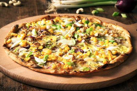 Fresh homemade pizza with green onion, corn, red onion, cashew nut and mozzarellaの写真素材
