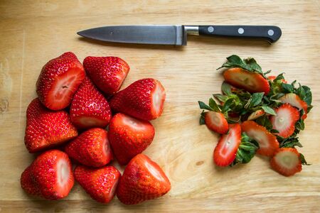 Freshly chopped strawberries on a chopping board with a knife