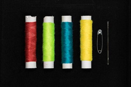 Sewing concept flat lay with cotton and a needle on a black background