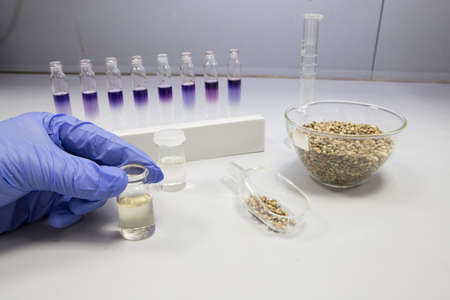 Cannabis oil testing in a laboratory. Scientist with a gloved hand analysing a vial of CBD oil
