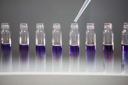 Analytical chemistry background. Small vials of purple chemical in a pharmaceutical laboratory....