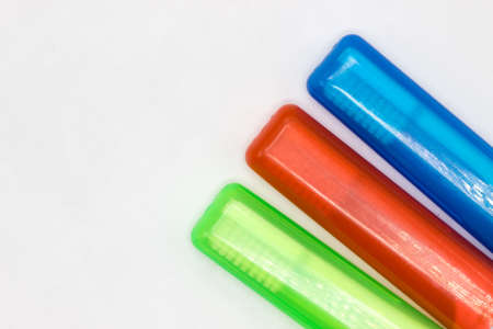 Colourful travel toothbrushes in cases on a white background