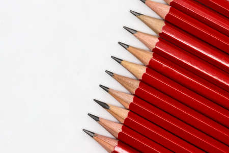 Row of sharp red drawing pencils on a white background with copy spaceの写真素材