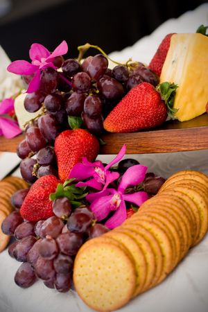 An appetizer selection of cheese, crackers, grapes and strawberriesの写真素材