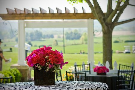 An outdoor cafe setting with a flower arrangement and green fields in the background.の写真素材
