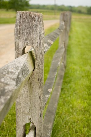Old rustic wooden picket fence on a farm next to a dirt road
の写真素材