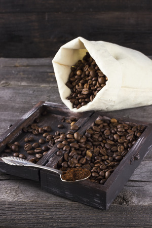 Bag with coffee grains and ground coffee on a wooden backgroundの写真素材