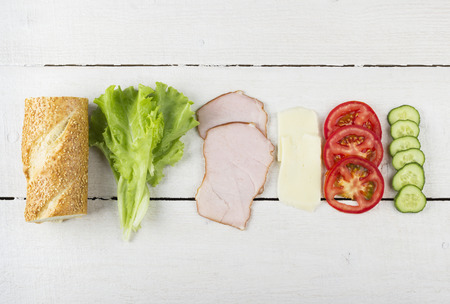 Ingredients for sandwich: lettuce, bacon, tomatoes, cucumber, cheese on a white wooden backgroundの写真素材