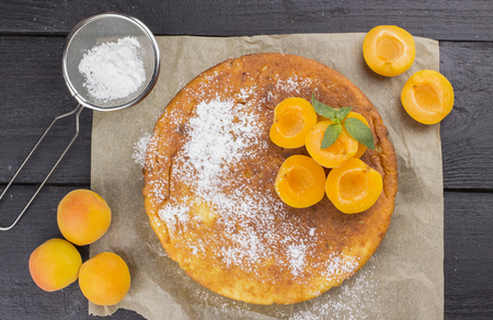 Cottage cheese pie with apricots on brown wooden background. Top viewの写真素材