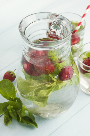 Summer cold drink with strawberry, mint and ice on a light backgroundの写真素材