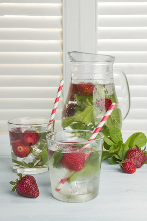 Summer cold drink with strawberry, mint and ice on a light backgroundの写真素材