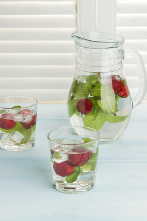 Summer cold drink with strawberry, mint and ice on a light backgroundの写真素材