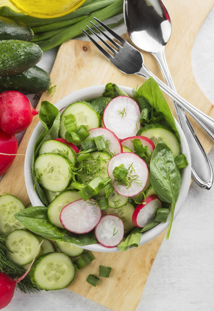 Salad with spinach, cucumber, radish in a bowl on a white background. Top viewの写真素材