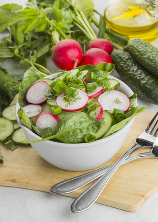 Salad with spinach, cucumber, radish in a bowl on a white background. Top viewの写真素材