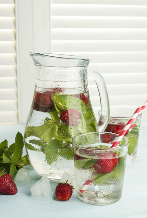 Summer cold drink with strawberry, mint and ice on a light backgroundの写真素材