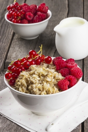 Oatmeal with raspberry and red currant on a wooden backgroundの写真素材