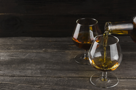 Cognac in two glasses on a dark wooden backgroundの写真素材