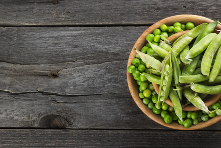 Green peas in wooden bowl on a white backgroundの写真素材